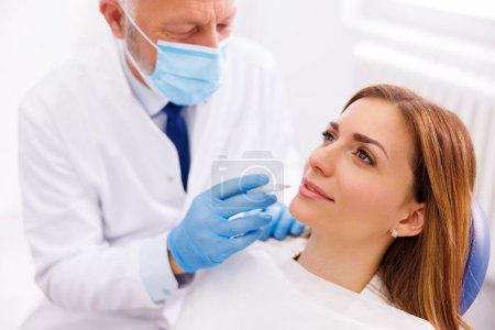 Detail des Zahnarztes Anwendung lokaler Betäubungsmittel auf Patientin zur Betäubung der Schmerzen vor dem Eingriff; Arzt Anwendung von Lippenfüllstoffen auf Patientin