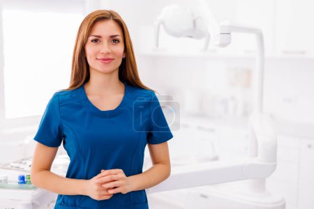 Photo for Portrait of young successful confident female doctor wearing uniform standing in ER and smiling with arms crossed - Royalty Free Image