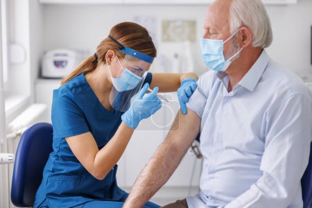 Ein älterer Mann mit medizinischem Mundschutz bekommt im Krankenhaus eine Impfung gegen Covid 19 oder die saisonale Grippe - Impfung, Immunisierung und Krankheitsvorbeugekonzept. Arzt impft älteren Patienten