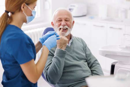 Téléchargez les photos : Médecin vérifiant les dents du patient au cabinet du dentiste ; senior au bilan dentaire - en image libre de droit
