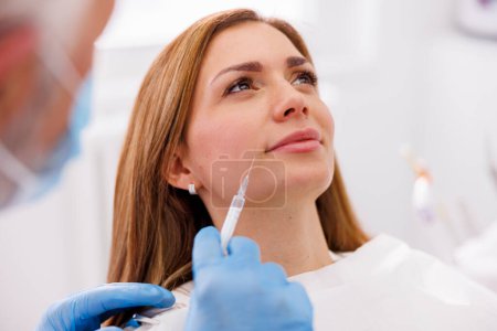 Woman having beauty treatment at doctor office, doctor applying hyaluron fillers