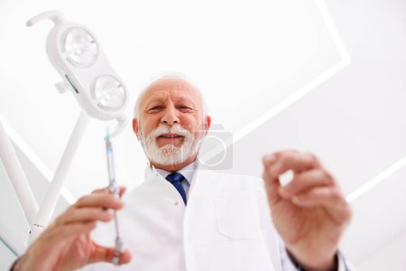 Niederwinkelaufnahme des Zahnarztes, der dem Patienten vor der oralen Operation Lokalanästhesie verabreicht; Arzt, der dem Patienten Hautfüllstoffe verabreicht