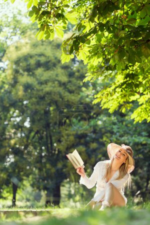 Téléchargez les photos : Jeune femme lisant un livre sur une journée d'été ensoleillée dans le parc - en image libre de droit