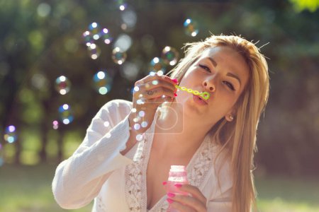 Téléchargez les photos : Portrait d'une belle jeune femme soufflant des bulles de savon dans le parc sur un été ensoleillé da - en image libre de droit