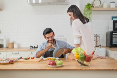 Foto de Feliz pareja joven cocinando juntos en el mostrador de la cocina en casa - Imagen libre de derechos