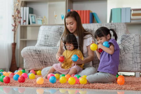 Foto de Feliz asiática familia madre y niño hija son jugando colorido bolas - Imagen libre de derechos