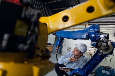 Foto de Ingeniero con control de inspección de seguridad del casco una soldadora de brazo robot con un sistema remoto en una fábrica industrial - Imagen libre de derechos