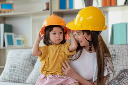 Foto de Madre asiática y su hija niña con casco de ingeniero amarillo, concepto de educación y ocupación - Imagen libre de derechos