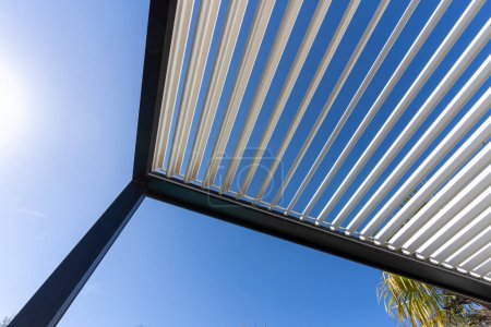 Aluminum pergola for outdoor patio against clear blue sky. Bottom view