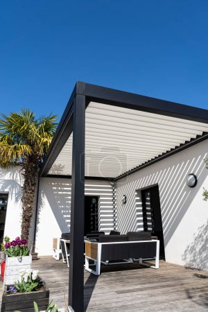 eco friendly structure d'ombre pergola en aluminium bioclimatique, auvent et toit patio, salon de jardin, chaises, barbecue en métal entouré d'aménagement paysager