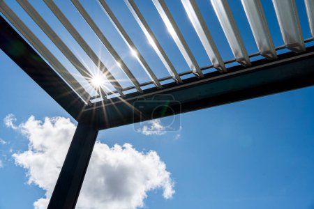Téléchargez les photos : Pergola patio extérieur tendance. les rayons du soleil traversent la structure métallique - en image libre de droit
