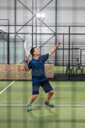 Foto de Pádel Jugador de tenis con raqueta en la mano. Pádel, sobre un fondo verde. - Imagen libre de derechos