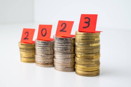 Foto de Montones de monedas, y billetes rojos que conforman el número 2023. Llegada de 2023 y perspectivas para el nuevo año. - Imagen libre de derechos
