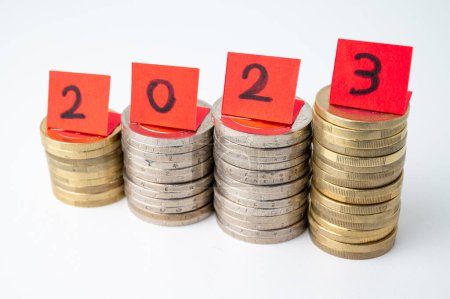Foto de Montones de monedas, y billetes rojos que conforman el número 2023. Llegada de 2023 y perspectivas para el nuevo año. - Imagen libre de derechos