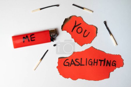 Photo for Red card with the word "gaslighting", with a lighter next to it with the word "me", and burnt red card with the word "you". Dynamics of gaslighting. - Royalty Free Image