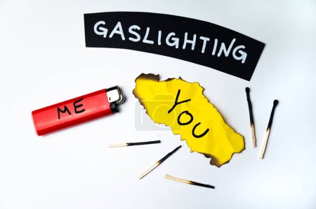 Photo for Word Gaslighting, on a black surface, next to a lighter with the word Me, and burnt yellow card with the writing You. Psychological meaning. - Royalty Free Image