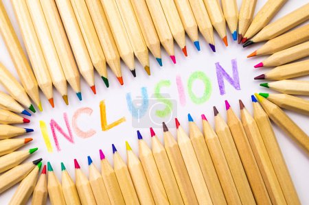 Foto de Colored pencils of different color, next to word "inclusion", written in various colors. Diversity and inclusion. - Imagen libre de derechos
