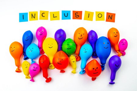 Balloons of different colors on a white surface, and text "inclusion". Inclusion, acceptance, integration and diversity.