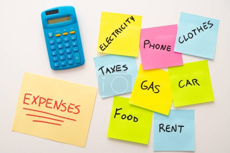 Photo for Yellow sheet, with red text "expenses", with calculator next to it and colored sticker sheets with list of expenses. Increases and cost of living. - Royalty Free Image