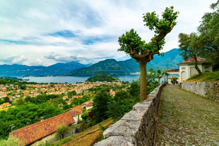 Photo for The panorama of Lake Como photographed from the town of Colonno, showing the town of Colonno, a stretch of cobbled road, and the panorama of the lake. - Royalty Free Image