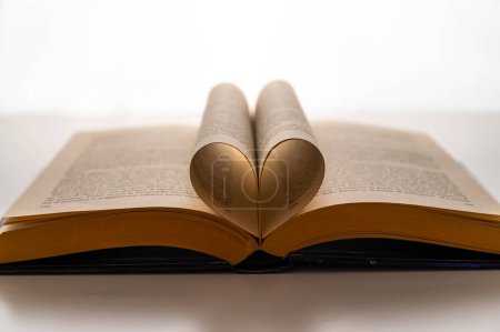 Foto de Libro abierto y páginas plegadas para formar un corazón, sobre un fondo blanco. Amor por la lectura. - Imagen libre de derechos
