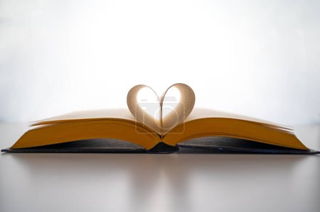 Foto de Libro abierto y páginas plegadas para formar un corazón, sobre un fondo blanco. Amor por la lectura. - Imagen libre de derechos