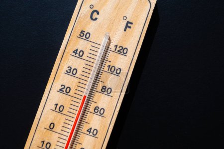 Thermometer auf dunkler Oberfläche. Steigende Temperaturen und globale Erwärmung.