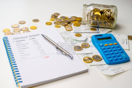 Notizbuch mit Familienbudget, Taschenrechner, Quittungen und Münzen daneben. Preiserhöhungen und wirtschaftliche Schwierigkeiten.