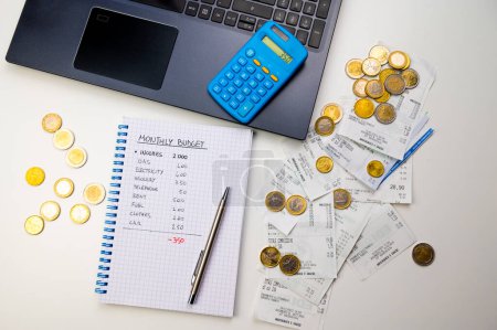 Notizbuch mit Familienbudget, Taschenrechner, PC, Quittungen und Münzen. Preiserhöhungen und wirtschaftliche Schwierigkeiten.