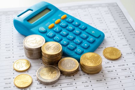 Calculadora y monedas por encima del cuadro de cálculo del presupuesto.