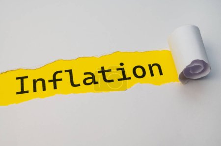 Surface jaune, avec le mot Inflation en noir, sous le carton blanc déchiré et roulé.