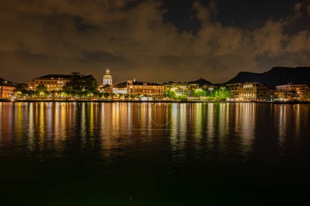 The city of Como, photographed in the evening, with the lakeside, the cathedral, the port and the moored boats.