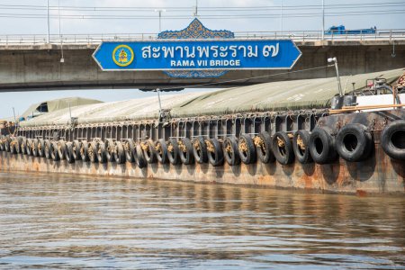 Foto de Un barco de transporte en el camino en el puente Rama 7 en el río Chao Phraya en la ciudad de Bangkok en Tailandia. Tailandia, Bangkok, diciembre de 2022 - Imagen libre de derechos