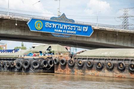 Téléchargez les photos : Un navire de transport sur le chemin au pont Rama 7 sur la rivière Chao Phraya dans la ville de Bangkok en Thaïlande. Thaïlande, Bangkok, décembre 2022 - en image libre de droit