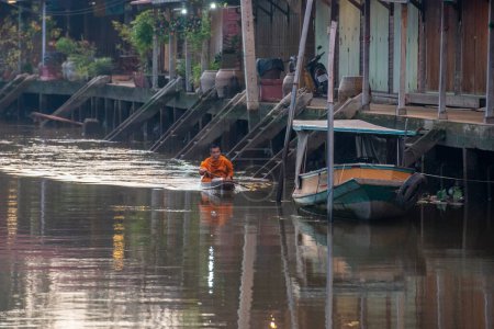 Téléchargez les photos : Un moine bouddhiste recueille l'aumône et visite les ménages sur un bateau à bois sur le Klong Chula de la rivière Mae Klong dans la ville d'Amphawa dans la province de Samut Songkhram en Thaïlande, Thaïlande, Amphawa, Novembre 2022 - en image libre de droit
