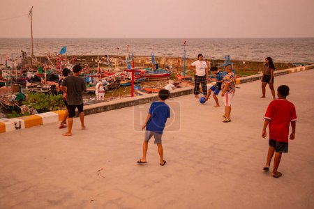 Téléchargez les photos : Enfants jouent au football au village de pêcheurs traditionnel sur la côte dans la vieille ville de Hua Hin dans la province de Prachuap Khiri Khan en Thaïlande, Thaïlande, Hua Hin, Décembre, 2022 - en image libre de droit