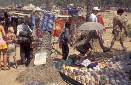 Foto de Tiendas y turistas en el antiguo mercado de pulgas de Anjuna en la costa en la ciudad de Anjuna en la provincia de Goa en la India, India, Goa, abril de 1996 - Imagen libre de derechos