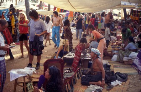 Photo for Shops and Tourists at the old style Anjuna Flea market on the Coast at the Town of Anjuna in the Province of Goa in India,  India, Goa, April, 1996 - Royalty Free Image