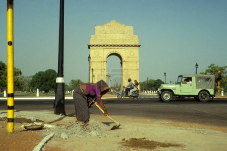 Téléchargez les photos : Une femme travaillant sur la route en face de la porte de Delhi dans la ville de New Delhi en Inde. Inde, Delhi, février 1998 - en image libre de droit