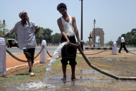 Foto de Un hombre salpica el agua en el parque frente a la Puerta de Delhi en la ciudad de Nueva Delhi en la India. India, Delhi, February, 1998 - Imagen libre de derechos