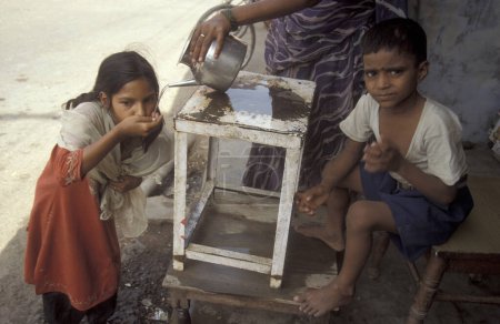 Téléchargez les photos : Une station d'eau publique gratuite d'une famille indienne dans la ville d'Agra dans la province de l'Uttar Pradesh en Inde. Inde, Agra, avril 1998 - en image libre de droit