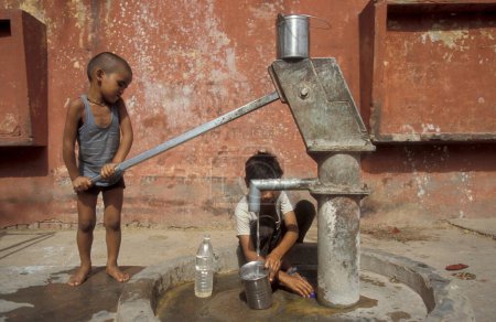 Téléchargez les photos : Une station d'eau publique gratuite et la source d'une famille indienne dans la ville d'Agra dans la province de l'Uttar Pradesh en Inde. Inde, Agra, avril 1998 - en image libre de droit