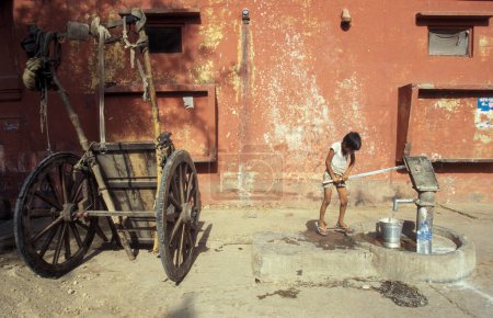 Téléchargez les photos : Une station d'eau publique gratuite et la source d'une famille indienne dans la ville d'Agra dans la province de l'Uttar Pradesh en Inde. Inde, Agra, avril 1998 - en image libre de droit