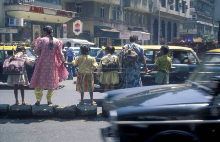 Téléchargez les photos : A Les femmes avec des enfants aiment traverser une route avec la circulation et les gens dans le centre-ville de Mumbai en Inde. Inde, Mumbai, mars 1998 - en image libre de droit
