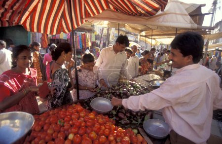 Téléchargez les photos : Légumes frais dans une rue de marché avec des magasins et des gens dans le centre-ville de Mumbai en Inde. Inde, Mumbai, mars 1998 - en image libre de droit