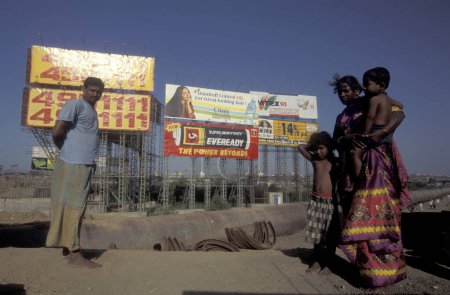 Photo for A Family in front of advertising at a water Pipeline in the centre of a slum in the city centre of Mumbai in India.  India, Mumbai, March, 1998 - Royalty Free Image