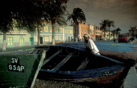 Téléchargez les photos : Bateau de pêche au marché aux poissons avec maisons coloniales dans la ville de Mindelo sur l'île de Sao Pedro sur les îles du Cap-Vert en Afrique. Cap-Vert, Santiago, mai 2000 - en image libre de droit