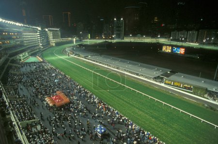 Téléchargez les photos : Une course de chevaux à l'hippodrome Happy Valley dans le centre de Hongkong dans la ville de Hongkong à Hongkong. Chine, Hongkong, mai 1997 - en image libre de droit
