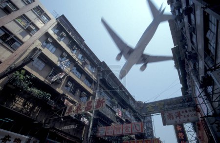 Téléchargez les photos : Un avion sur le chemin de l'ancien aéroport de Hongkong Kai Tak dans la ville de Hongkong à Hongkong. Chine, Hongkong, mai 1997 - en image libre de droit