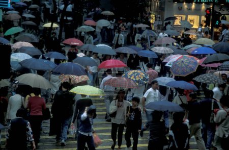 Téléchargez les photos : Peuple par la pluie avec des parasols sur une route dans le centre de la ville de Hongkong dans la ville de Hongkong dans Hongkong. Chine, Hongkong, mai 1999 - en image libre de droit